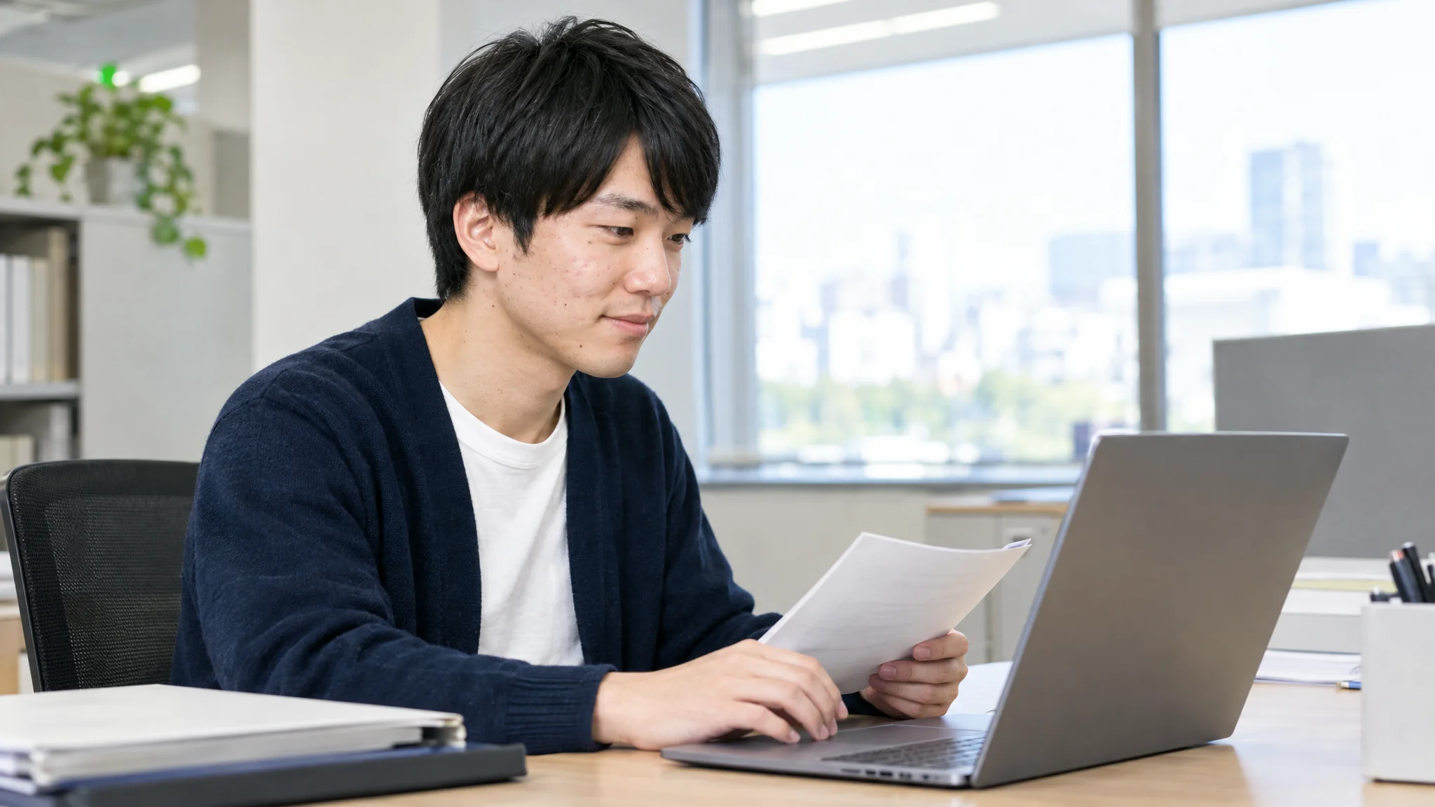 In a bright meeting room, a Japanese IT administrator operates a tablet while checking the management screen of an AI meeting minutes tool. The screen displays a Japanese dashboard with usage rate graphs and security setting checklists. The administrator is focused intently on the screen, performing a final check for internal deployment.
