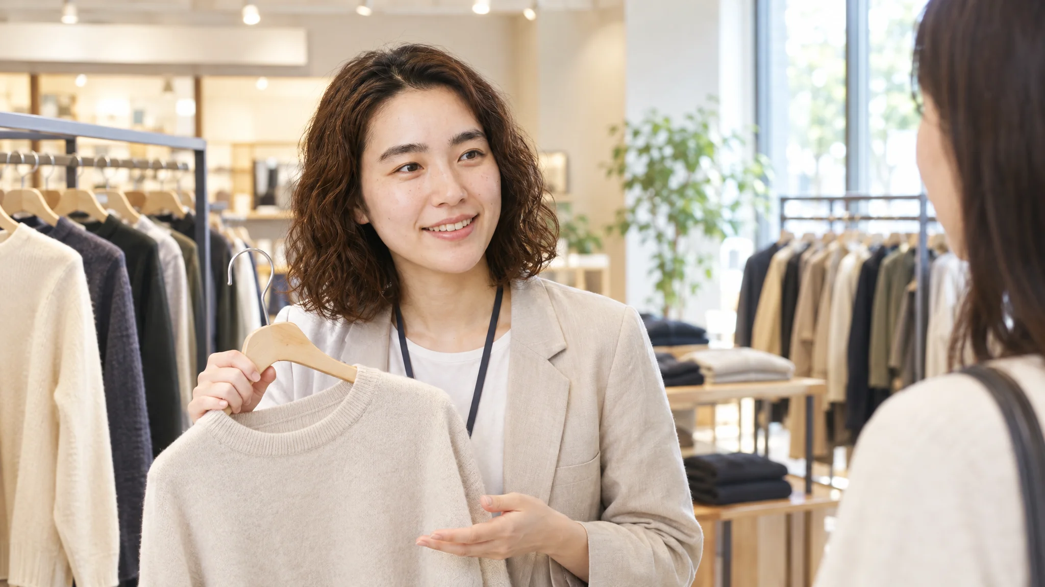 The backroom of a Japanese retail store. A Japanese female staff member is holding a tablet, reviewing an AI analysis report that shows how her social media posts contributed to e-commerce sales. Her gaze is focused on the screen in her hand, and she has a satisfied expression. On the wall, graphs showing not only sales targets but also trends in customer satisfaction and social media engagement are posted in Japanese.